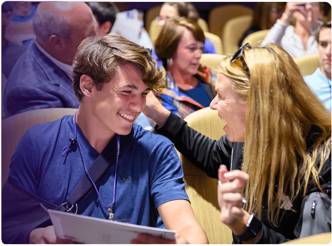 Student and family member smiling at each other.